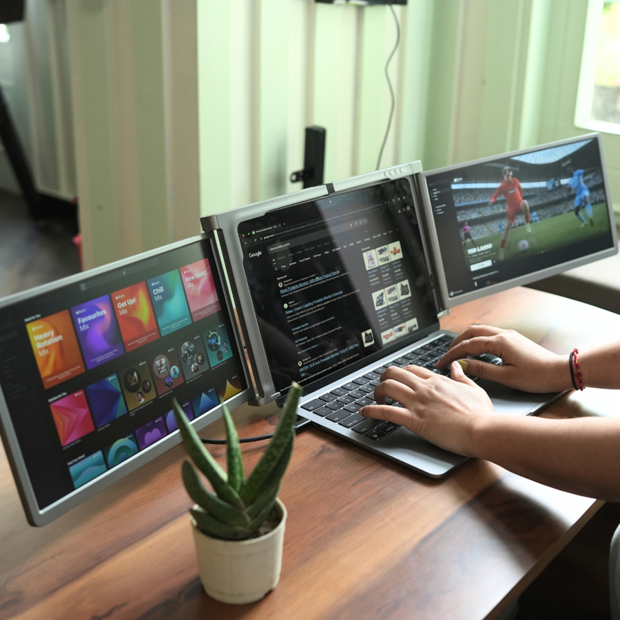 Person using RIITEK 13.3 inch portable triple screen monitor on a wooden desk with streaming and media open across three displays